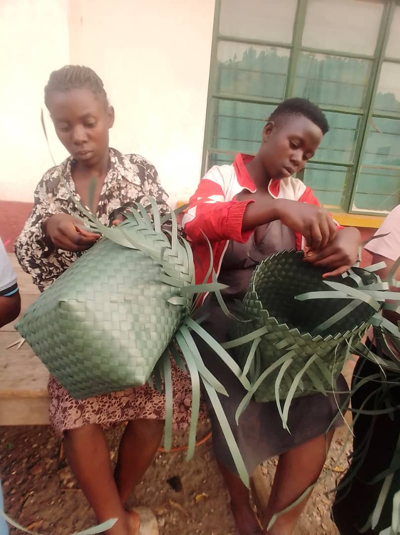 Girls weaving green baskets during a community training session.