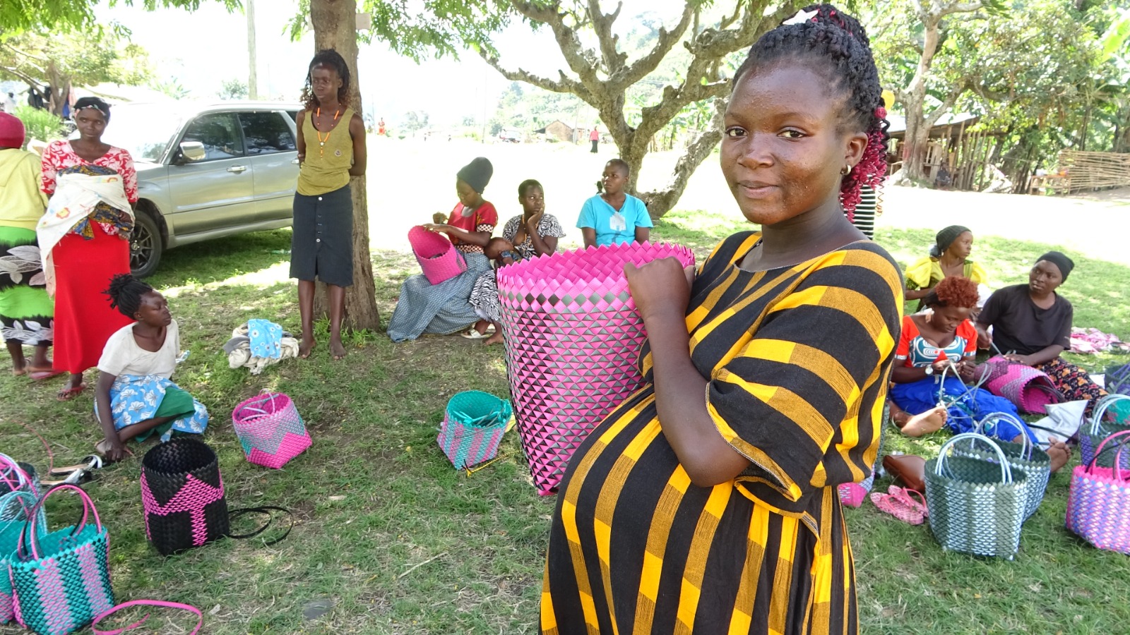 Teen mother holding a handmade woven bag.