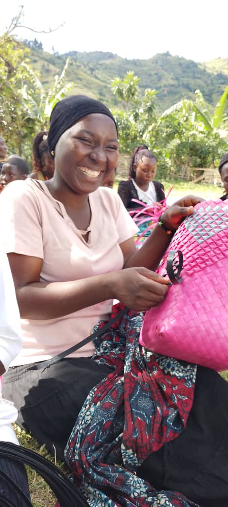 A smiling young woman weaves a basket during training.