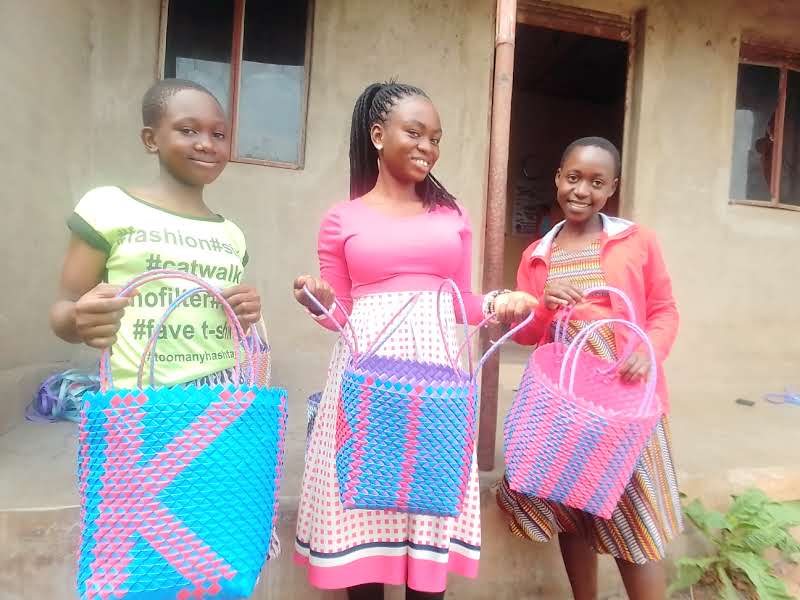 Teenage girls hold baskets they made during weaving training.