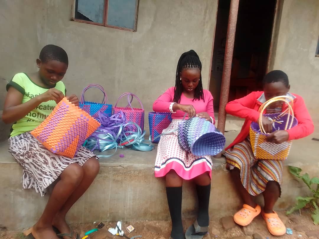 Teenage girls weave baskets together during skills training.