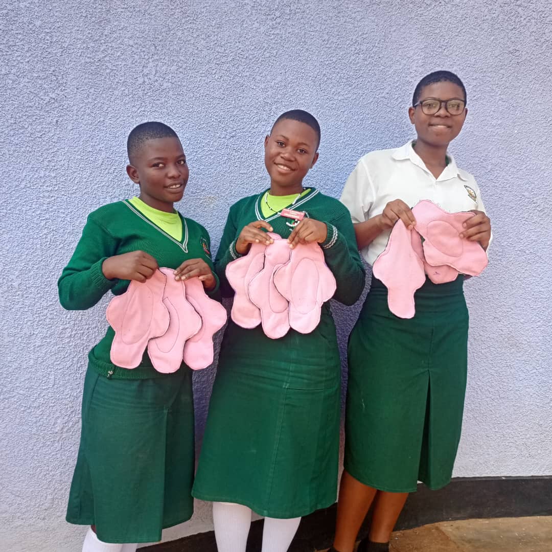 Teenagers holding reusable menstrual pads during a school health initiative.
