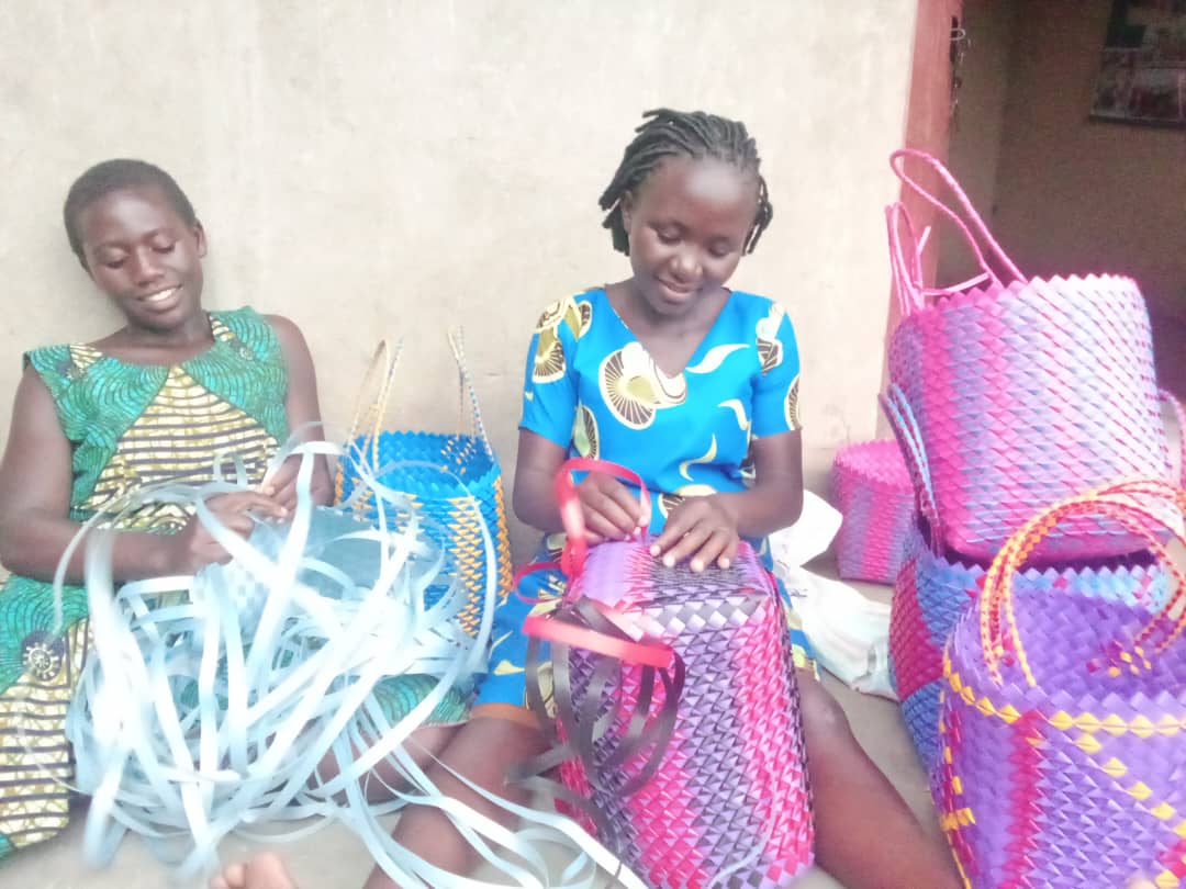 Teenagers practice weaving as part of a community education and crafts session.