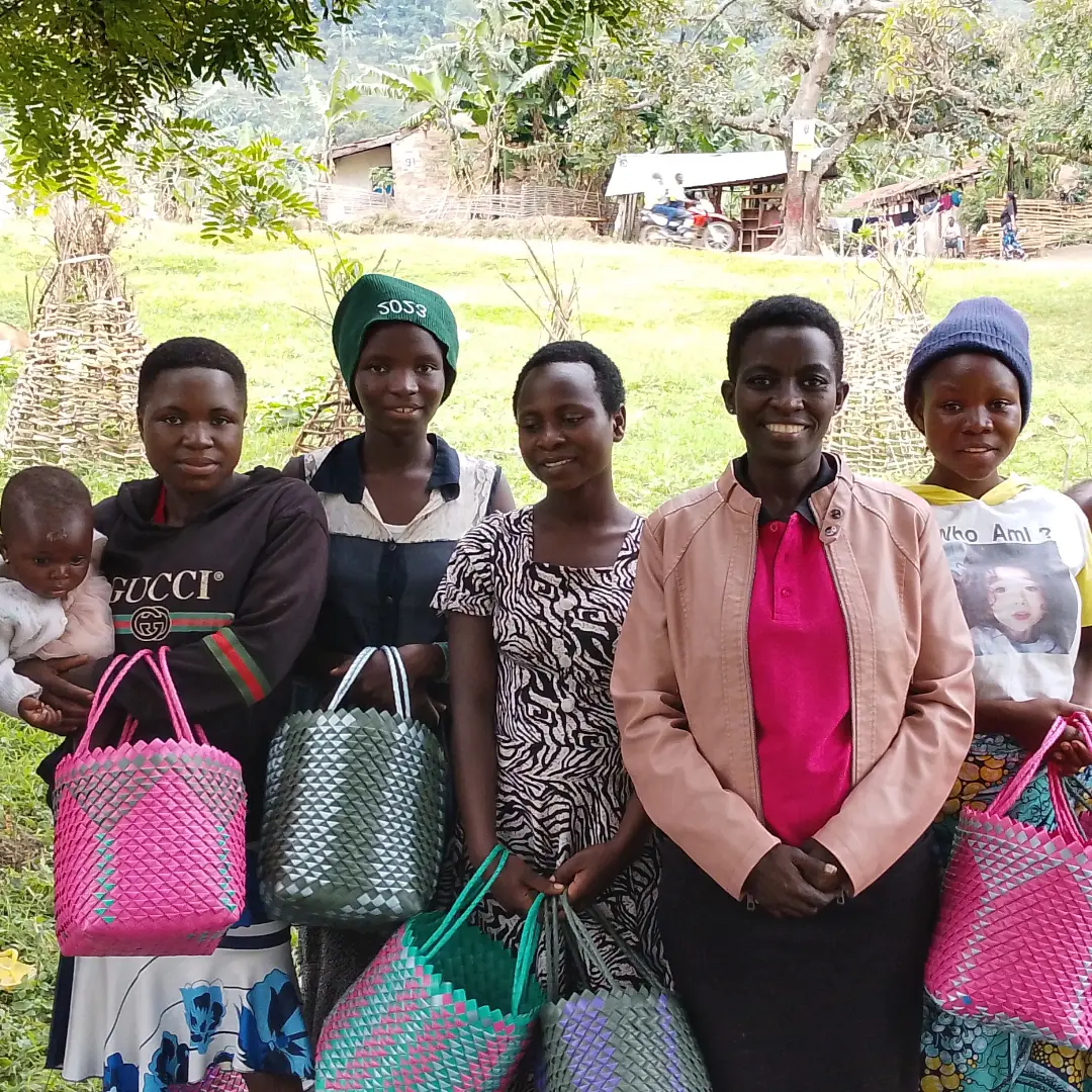 Young women standing outdoors holding colorful handmade woven bags.