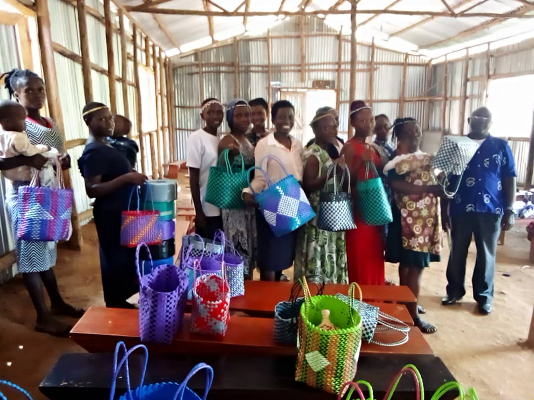Women hold woven baskets made through community education and craft training.