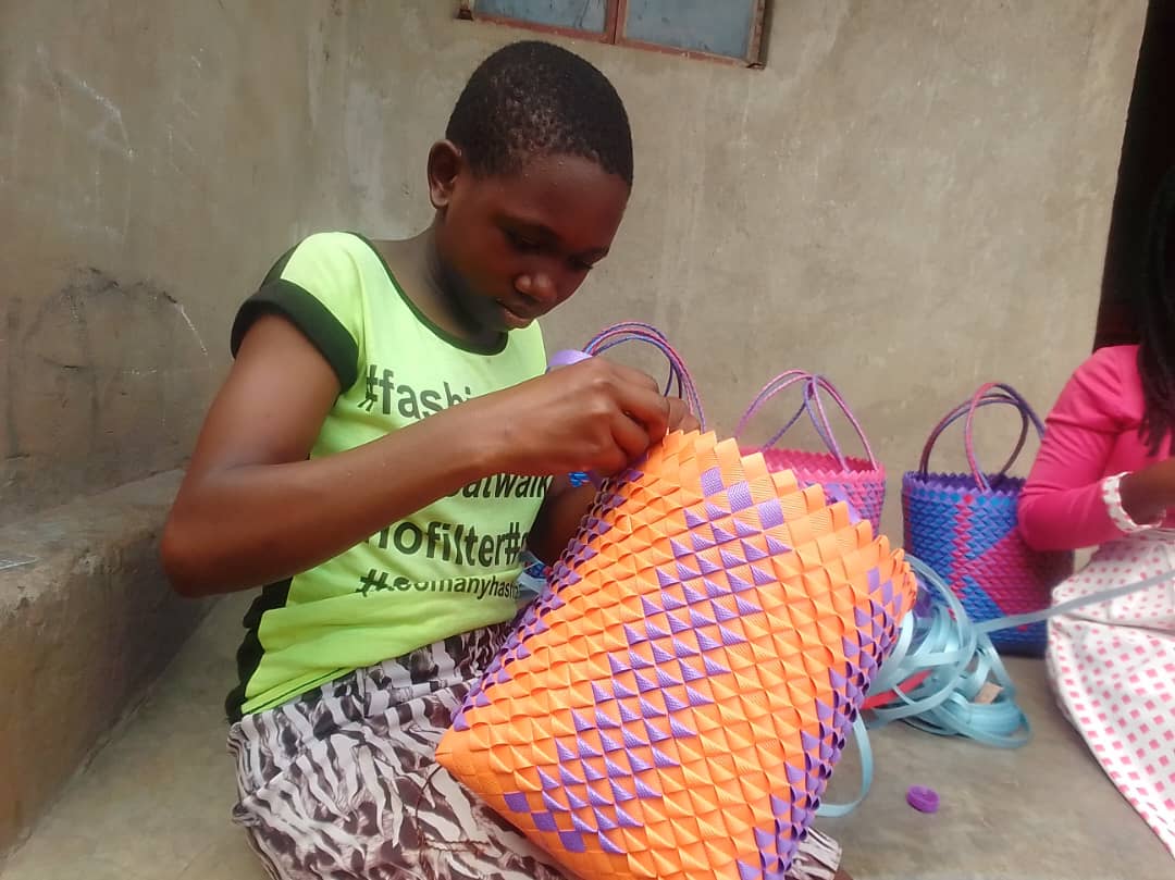 A young teenager weaves baskets during training in Uganda.